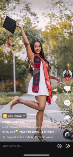 a woman in a graduation cap and gown is dancing on the street with her arms up