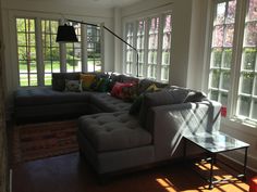 a living room filled with furniture and windows covered in sun shining through the window panes