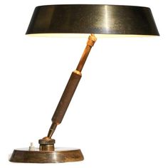 a lamp that is on top of a wooden base and has a black shade over it