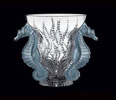 a glass vase with two seahorses on the side and bubbles in the bottom