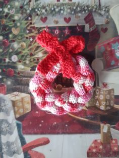 a red and white knitted wreath hanging from a christmas tree