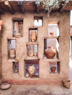 clay pots and vases are displayed on shelves in an adobe - style building,