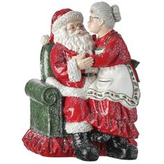 a statue of santa and mrs claus sitting on a green chair, holding each other