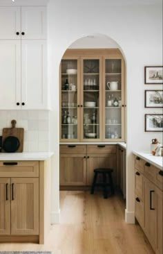 a kitchen with wooden cabinets and white counter tops, along with an arched doorway leading to the dining room