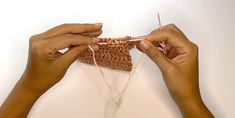 two hands crocheting the ends of a piece of cloth with yarn on it