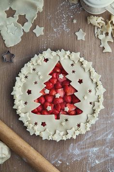 a christmas tree shaped pie on top of a wooden table next to cookie cutters