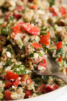 a close up of a salad in a bowl with a spoon on the side,