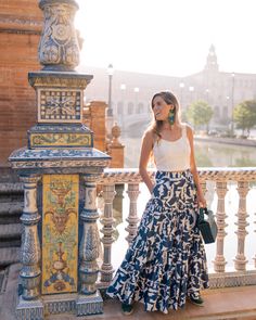 a woman in a long skirt standing on a balcony