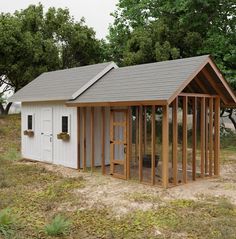 a small white shed sitting in the middle of a field