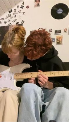 two people sitting on a couch playing guitar