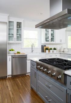 a modern kitchen with stainless steel appliances and white cabinets, wood floors, and hardwood flooring