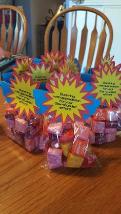 some candy wrapped in plastic sitting on top of a wooden table next to two chairs