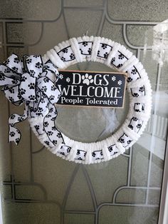 a white wreath with black and white dog paw prints on it that says dogs welcome