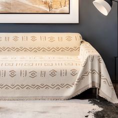 a living room with a couch covered in a white blanket next to a painting on the wall