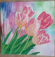 beaded flowers are displayed on top of a card with green stems and pink tulips