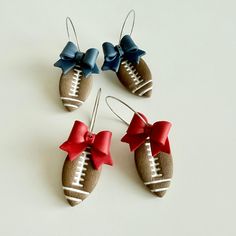 three pairs of earrings with bows and footballs on them, all decorated in different colors