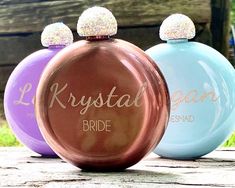 three different colored perfume bottles sitting on top of a wooden table