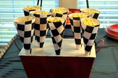 black and white checkered paper cups with popcorn in them sitting on a red tray