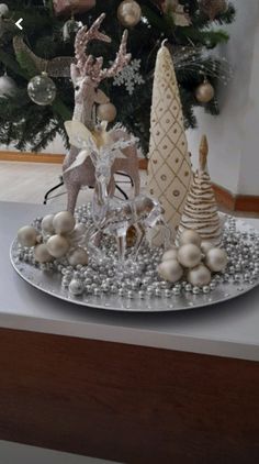 a christmas tree with ornaments on it in front of a silver platter filled with white balls