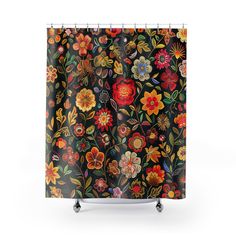 a shower curtain with colorful flowers and leaves on black fabric, hanging from a metal rod