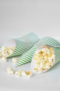 two paper cones filled with popcorn on top of a table