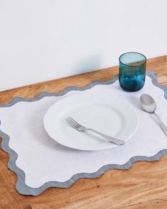 a white plate with silverware on top of it next to a glass and spoon