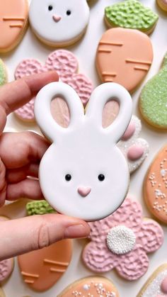 a person holding up a cookie shaped like a bunny and some cookies in the shape of bunnies