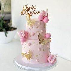 a pink and gold cake with butterflies on it