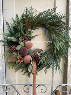 a wreath with pine cones and greenery hangs on the front door of a house