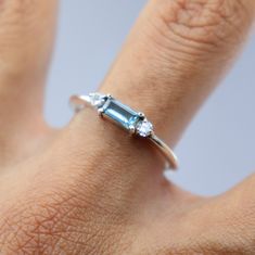 a woman's hand with a ring on top of her finger and an emerald stone in the middle