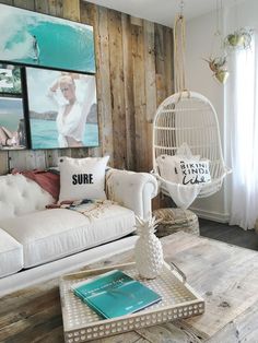 a living room filled with white furniture and pictures on the wooden wall behind the couch