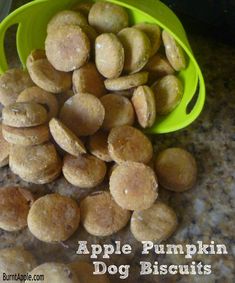 a pile of apple pumpkin dog biscuits next to a green bowl