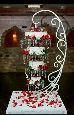 a three tiered wedding cake with red roses on the bottom and white icing