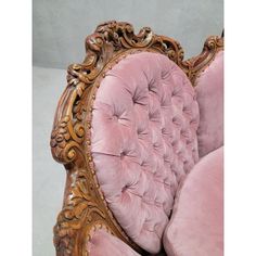 an ornately carved chair with pink velvet upholstered