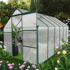 a green house surrounded by flowers and greenery