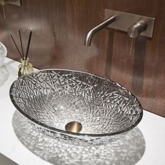 a glass bowl sink sitting on top of a counter next to a faucet