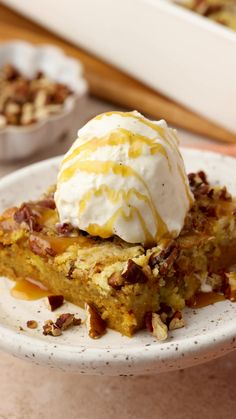 a white plate topped with a piece of cake covered in whipped cream and pecans