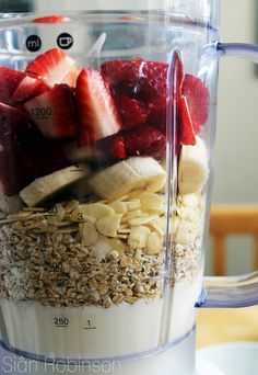 a blender filled with granola, strawberries and bananas