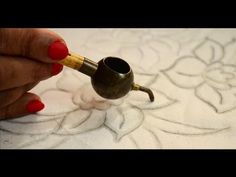 a woman is holding a pipe in her hand and painting it with red nail polish