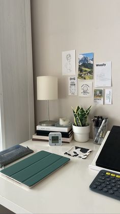 a laptop computer sitting on top of a white desk next to a calculator