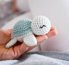 a small crocheted turtle is held in someone's hand while they are laying down