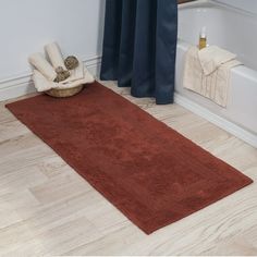 a bath room with a toilet and a rug on the floor in front of a tub