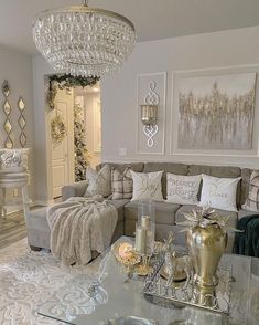 a living room filled with furniture and a chandelier hanging above the couches