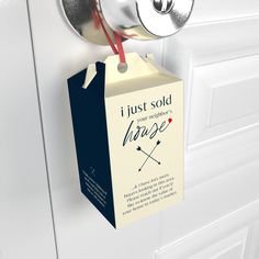 a wine box hanging from the side of a white door with a red string attached to it