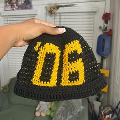 a hand holding up a crocheted hat with the letter d on it