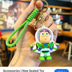 someone holding up a keychain with a toy story character on it