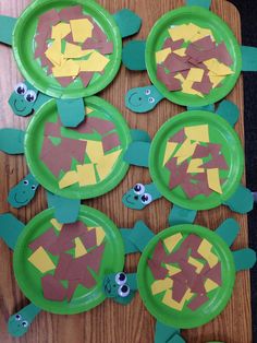 paper plates with cut out turtles on them sitting on top of a wooden table covered in construction paper