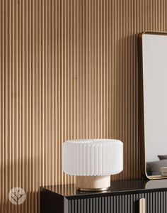 a white lamp sitting on top of a wooden table next to a mirror and dresser