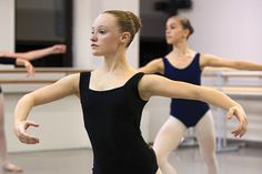 two women in black leotards are practicing ballet