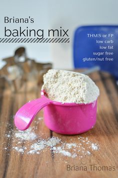 a pink measuring cup filled with flour on top of a wooden table